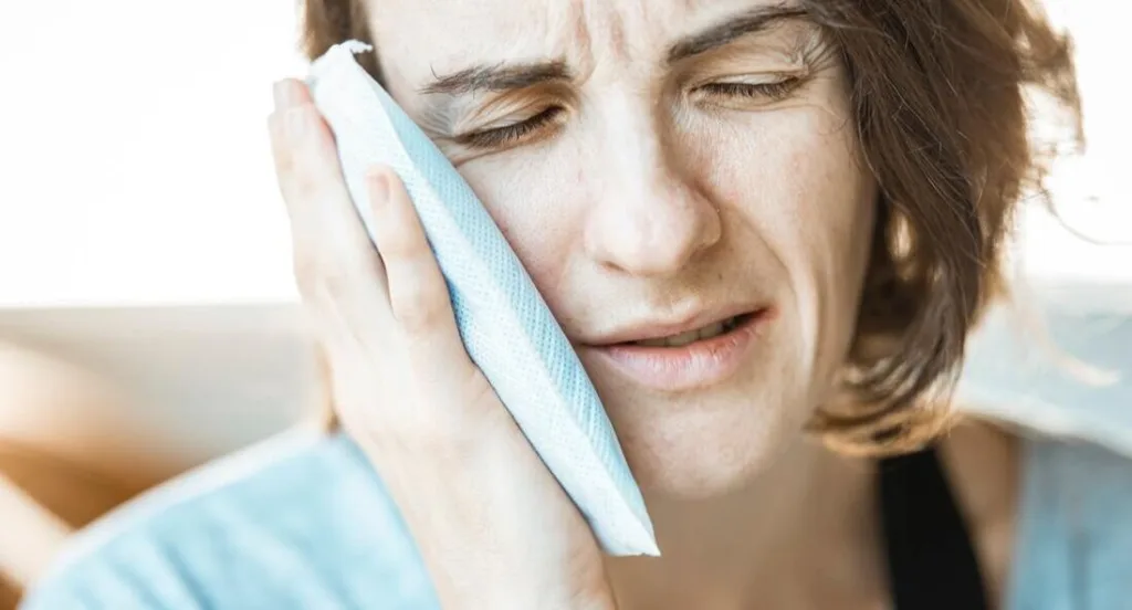 Woman holding ice pack up to jaw for teeth pain